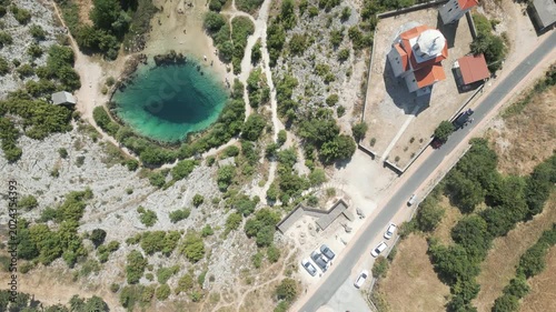 Top down drone view of the unique Cetina river source karst spring and historic Orthodox church, Croatia.