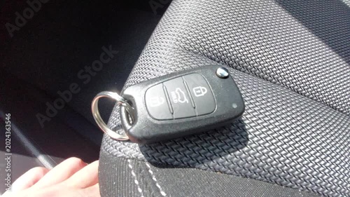 Car key fob with remote control buttons lying on a black fabric car seat