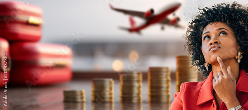 woman reflects on travel expenses, with stacked coins, red luggage, and a plane taking off in the background. Budget and trip planning concept