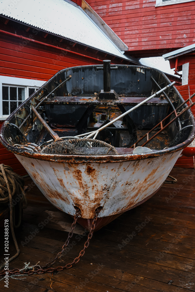 Obraz premium Rustic Maritime Scene with Old Fishing Boat, Nautical Equipment on Pier, Traditional Red Fishery Warehouse, Coastal Industry