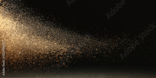 Golden glitter particles swirl and dance in a beam of light against a dark background, creating a magical and ethereal effect.