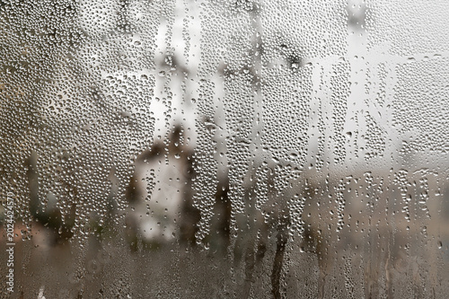 Foto Closeup of window covered with water droplets and condensation, blurred outdoor scene visible through wet glass, texture and abstract detail, dampness concept