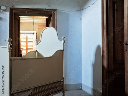 Abandoned bedroom with vintage iron bed inside historic Italian villa