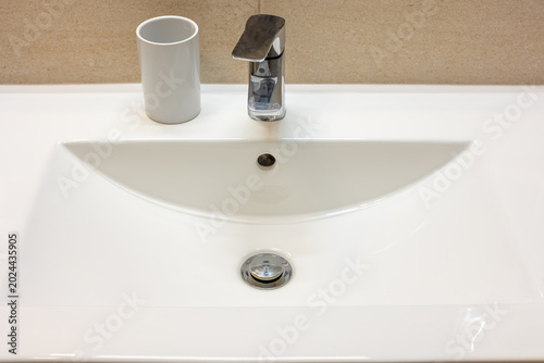 Front view of detail of a bathroom sink with a chrome faucet. Horizontally.