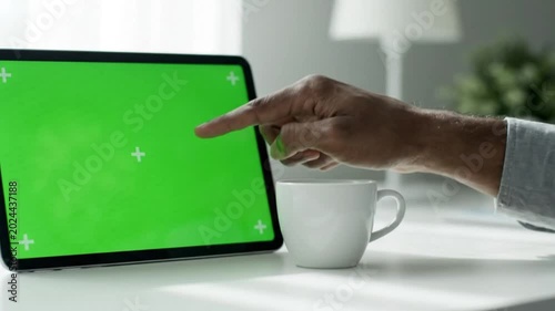 Person using a tablet with a green screen in a workspace