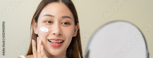Foto wellness care concept,  young woman looking at the mirror and applying facial sk