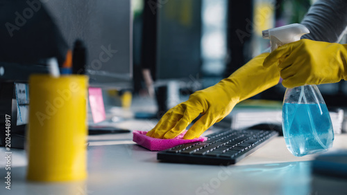 Person cleaning computer keyboard with spray.