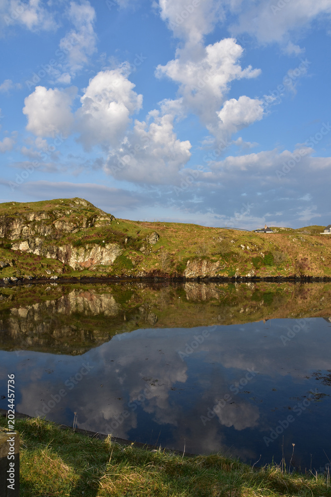 Fototapeta premium Clouds and Rocky Landscape in the Loch Reflection