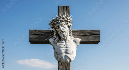 Detailed stone sculpture of a sacred figure wearing a sharp crown of thorns while mounted on a large wooden cross under a clear blue sky, thorns, light, grace