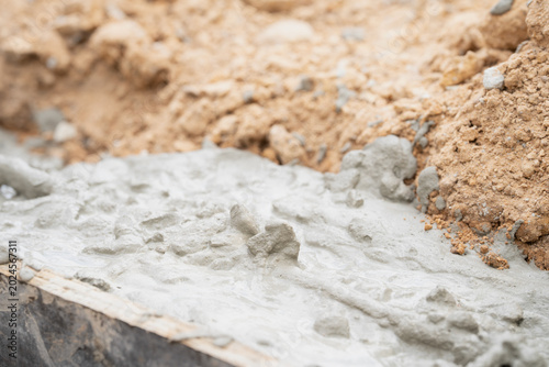 Foto Wet Cement Texture: Close-up of wet cement poured into a wooden form, showcasing the granular texture and the rough aggregate within, suggesting construction and building in progress
