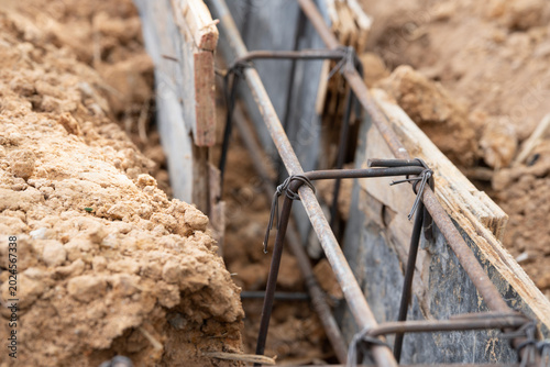 Concrete Foundation Reinforcement: Close-up view of rebar and wooden formwork for a concrete foundation, ready for construction.