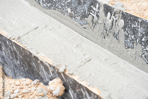 Foto Fresh Cement Trough Construction: A close-up view of a newly poured cement trough, detailing the wet concrete and rough texture of the formwork, ready for hardening