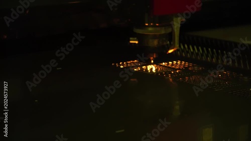 Industrial footage of a high-precision fiber laser cutting machine engraving and cutting a metal plate with intense sparks.