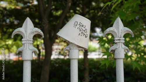 Bild auf Leinwand Disposable paper coffee cup stuck on an iron fence in an outdoor park area, in South Korea