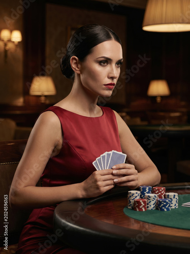 Elegant woman playing poker with cards in a dark casino
