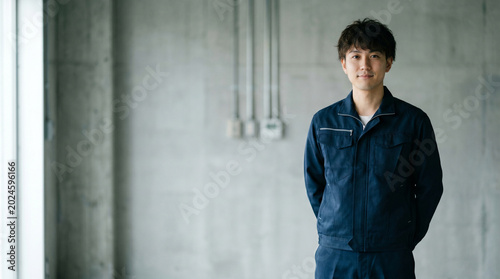 Plakat 手を後ろで組んで立つ設備管理・電気工事士の男性、求人・採用イメージ