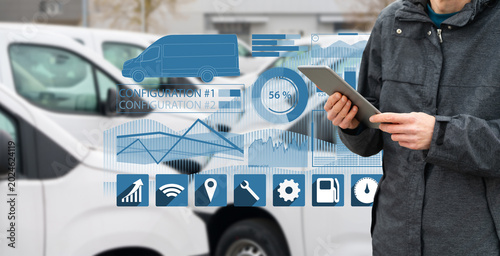 Fleet manager with digital tablet supervising rows of white delivery vans