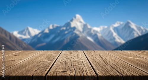 Rustic wooden table surface foreground with blurred snowy mountain peaks under a clear blue sky, perfect for product display and mockup, altitude, snow, texture