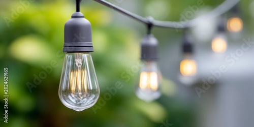 old vintage light bulbs hanging on outdoor string lights in front of a house