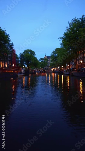 Cinematic POV boat ride through
Amsterdam canals at blue hour passing illuminated historic bridges