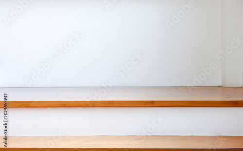Close-up view of wooden stairs with clean white risers. A minimalist interior design featuring strong horizontal lines, authentic natural wood texture, and soft natural light for background.