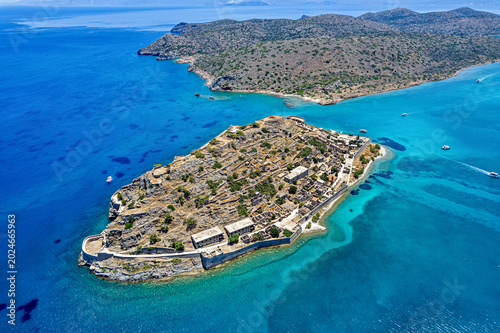 Aerial view of Spinalonga island in Crete, Greece, Europe, showing historic ruins, stone walls, and turquoise waters of the Aegean Sea.