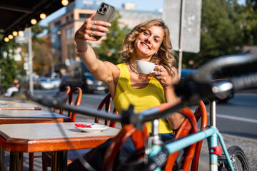 Smiling woman taking a selfie with coffee at outdoor cafe