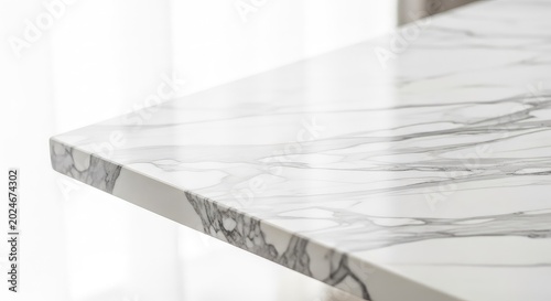 A close-up side angle of a polished white marble tabletop showing elegant grey veins across a smooth stone surface with natural bright light, white, home, clean