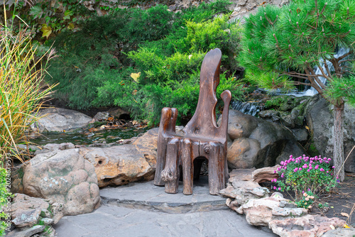 Wooden chair in a garden near a small stream