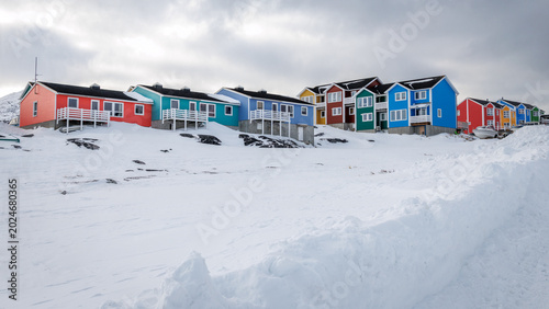 Foto Colorful Inuit houses on a snowy hillside with winter clouds and arctic resident