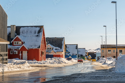 Schilderij op canvas Arctic winter street with wooden Inuit houses, snow-covered roofs and sea in the