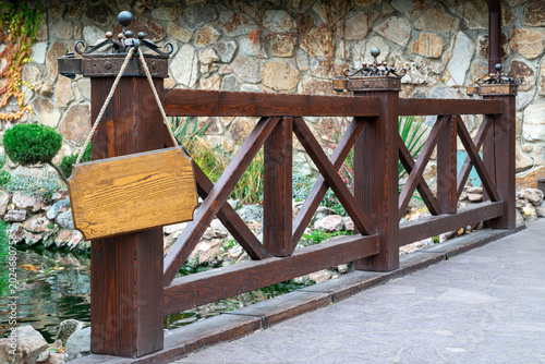 Wooden bridge with empty sign near a pond