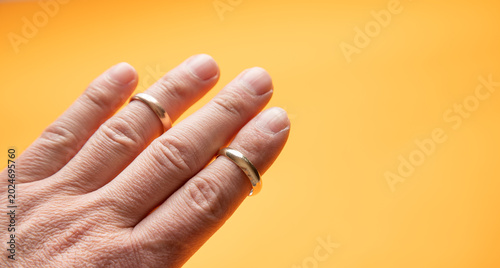 Foto Male hand with a golden ring on the yellow background.