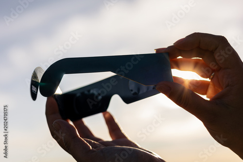 Cuadro en lienzo Hands holding solar eclipse glasses seeing bright sun rays during a celestial ev