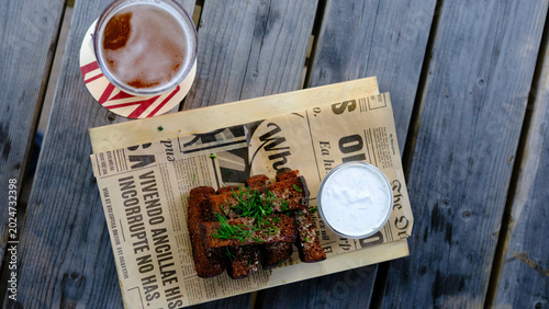 Appetizer: garlic croutons made from black bread, served on newspaper on a wooden pallet-style tray.