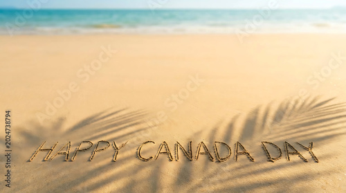 Happy canada day message written in beach sand Canada Day