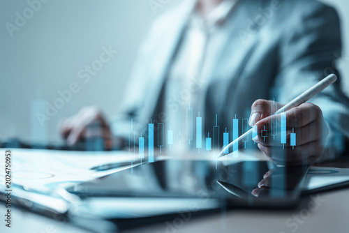Fotografie Business professional using stylus on tablet with stock candlestick chart overlay, representing investment analysis, portfolio management, market trends, and financial strategy