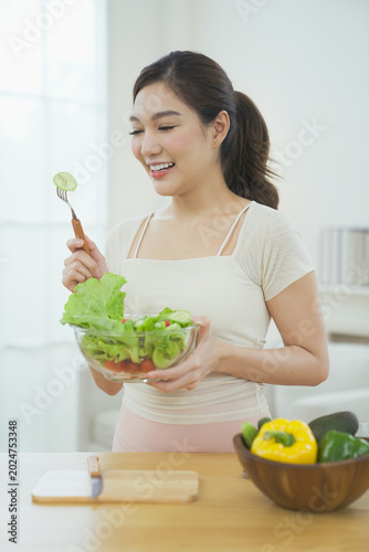 Foto Happy young woman enjoying healthy organic salad at home