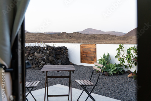 Billede på lærred Minimalist outdoor terrace with table and chairs overlooking a volcanic landscap