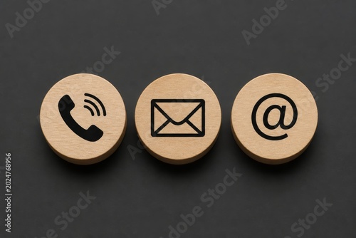Three round wooden tokens display icons for a phone, envelope, and email address, representing contact methods.