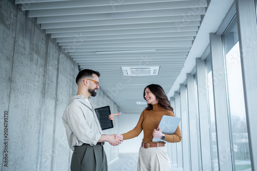 Foto Business partners shaking hands making agreement in office hallway