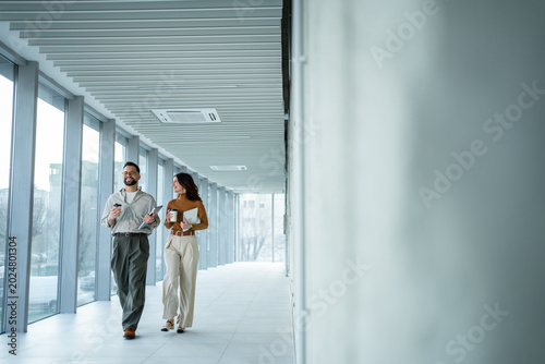 Φωτογραφία Business coworkers walking in modern office hallway discussing work