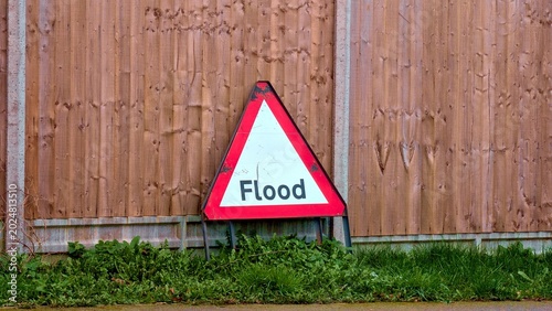 Photos Flood warning road sign, temporary triangular uk traffic sign on grass patch aga