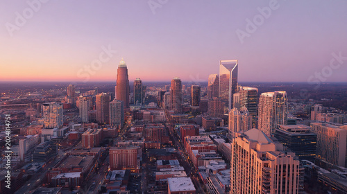 A stunning aerial view of a modern city at sunset, showcasing the skyline with soaring skyscrapers and a vibrant horizon painted in warm hues
