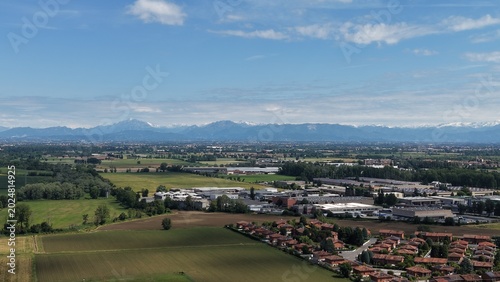 Photography Urban Sprawl Meets Countryside: An aerial view captures the contrast between a sprawling industrial and residential area and the surrounding green fields and distant mountains