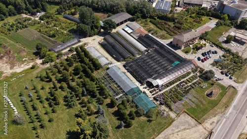Drone aerial footage of a large plant nursery with greenhouses, tree rows and ornamental plants in the Lombardy countryside of Northern Italy.