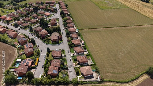 Schilderij op canvas Suburban Serenity: An aerial view reveals a tranquil residential neighborhood, a harmonious blend of neat houses and green spaces, adjacent to expansive agricultural fields