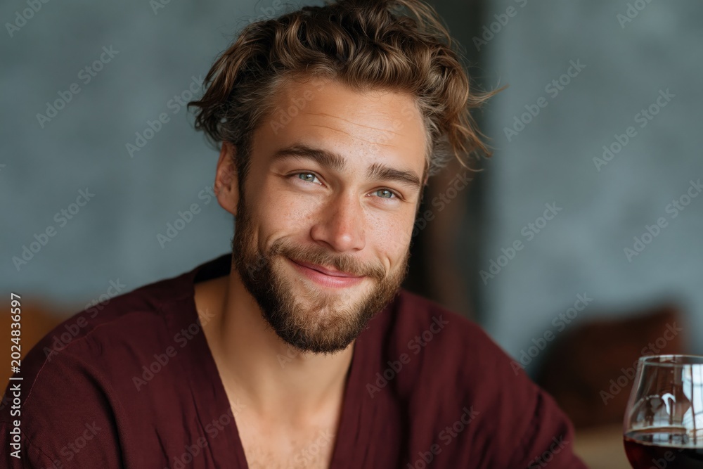 Obraz premium Young man smiling while seated indoors at cafe table