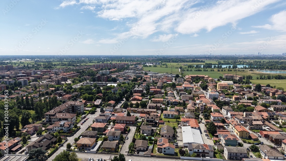 Obraz premium Aerial View of a Quaint Town: An aerial perspective reveals a charming European town with red-tiled roofs, nestled amongst green fields and trees, Pantigliate, Lombardy, Italy,