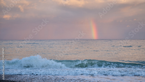 Obraz na płótnie Rainbow over sea waves at sunset